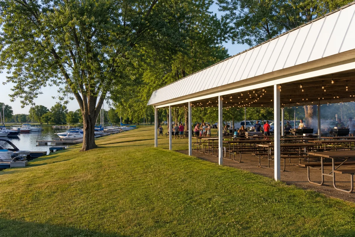 The outdoor pavilion with picnic tables and string lights on the lawn near the docks