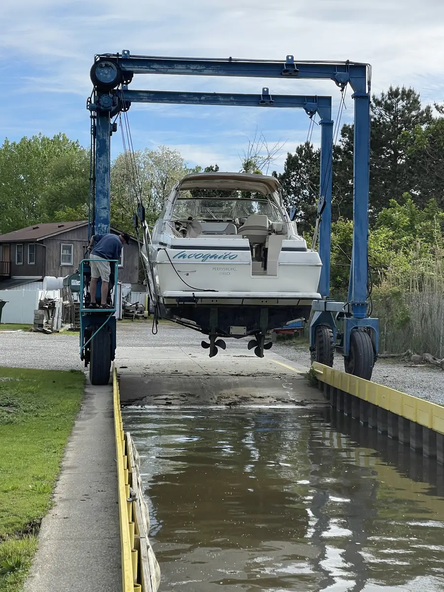 A powerboat in the travel lift slings above the wet well