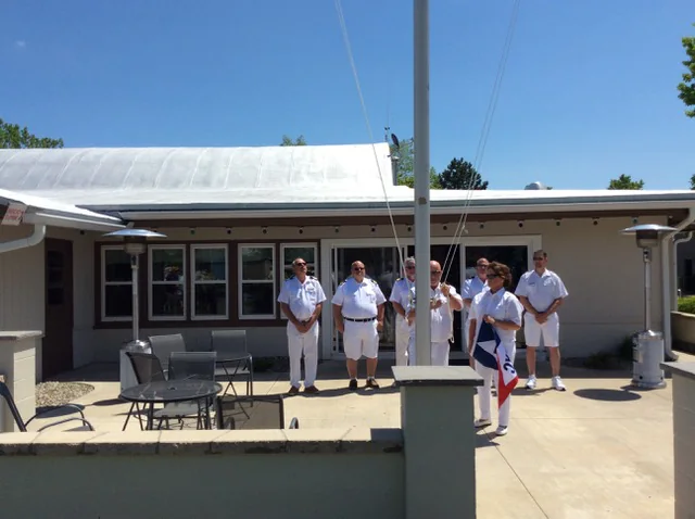Club members in dress whites lined up at the clubhouse patio for a Memorial Day flag raising
